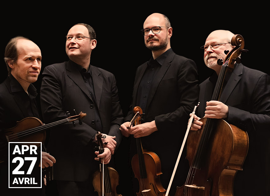 A photograph of Quatuor Élysée, a string quartet, featuring four musicians dressed in black formal attire holding string instruments. The background is completely black, emphasizing their figures. All four musicians are smiling, conveying a sense of camaraderie and warmth.