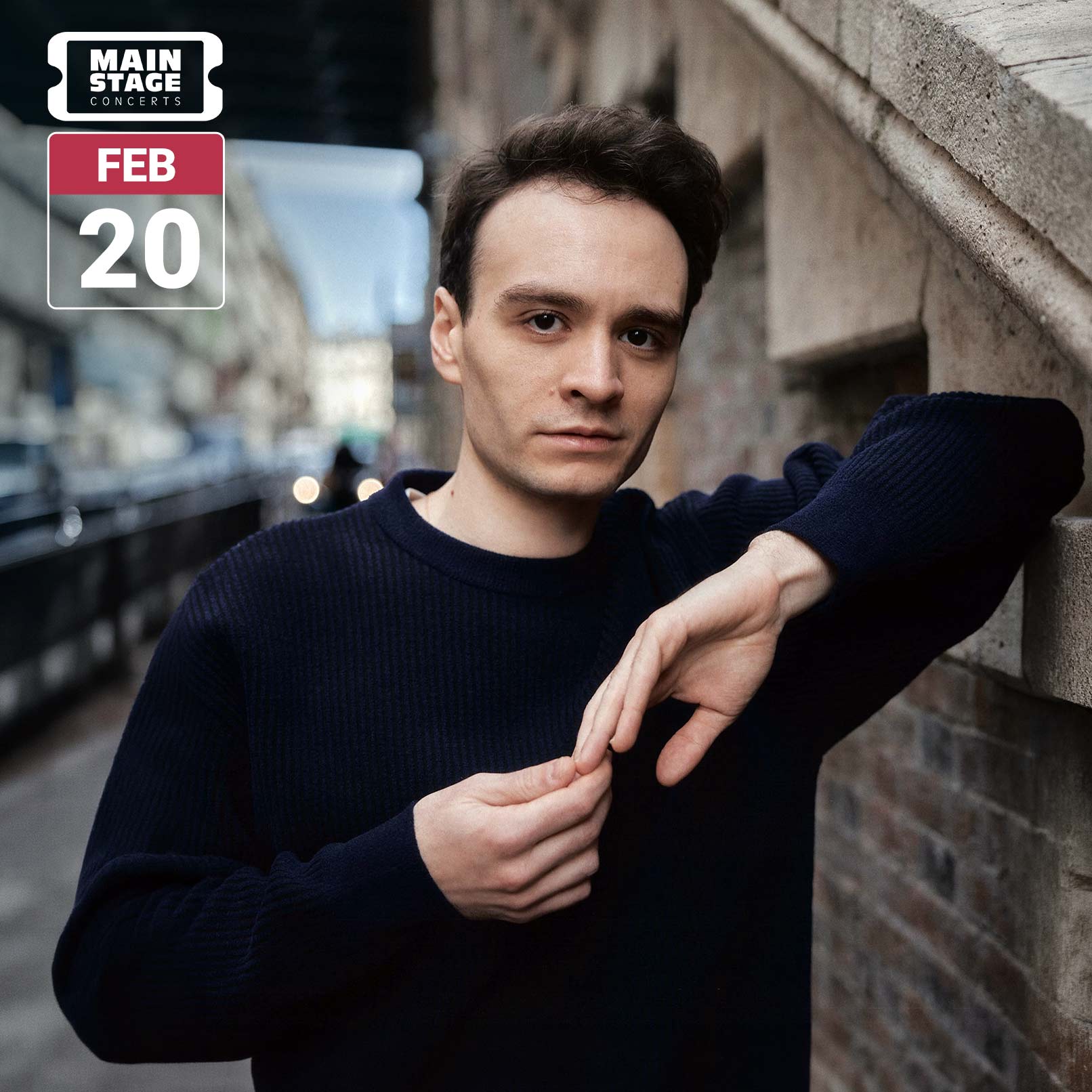 Concert graphic featuring pianist Jonathan Fournel in a navy sweater, leaning against a stone wall on a city street and looking toward the camera. His hands rest together in front of him. A white Main Stage Concerts logo and a red-and-white February 20 date badge appear in the upper left.